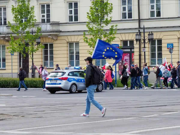 Siyasi miting sırasında şehir meydanında yürüyen Polonya ve Avrupa bayrakları taşıyan protestocular