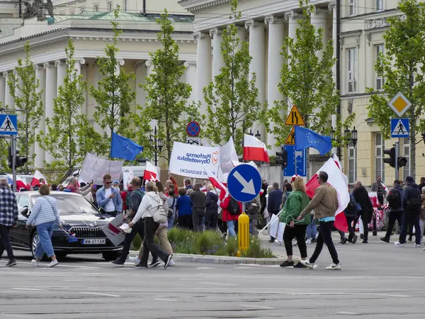 Varşova 'da düzenlenen yürüyüş sırasında arkaplanda tarihi binalar bulunan ulusal bayraklar taşıyan Polonyalı göstericiler