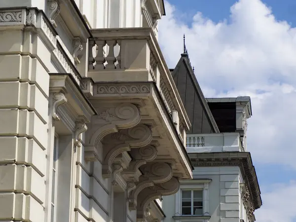 Süslü taş balkon dekoratif detaylarla ve mavi gökyüzünün altında klasik mimari elementlerle