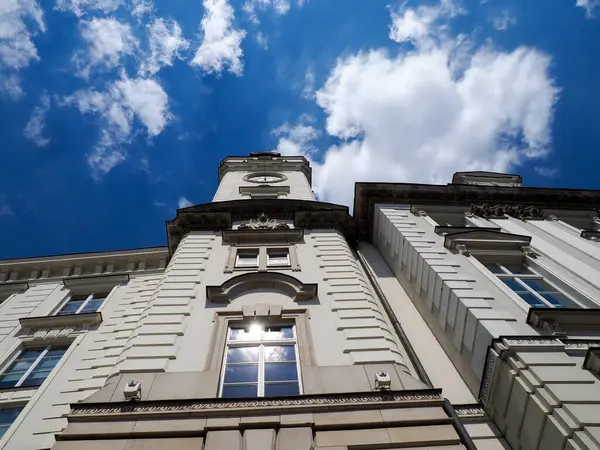 Parlak mavi bulutlu gökyüzüne bakan süslü camlı tarihi taş binanın dramatik alçak açılı manzarası
