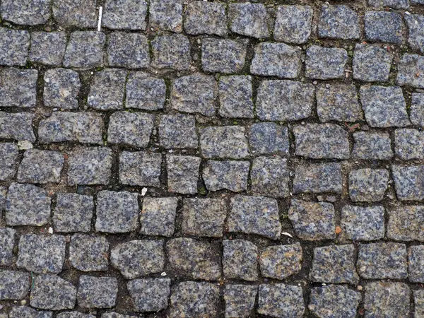 Yıpranmış kaldırım dokusu, geleneksel Avrupa sokak modelinde doğal eskimiş taş blokları gösteriyor.