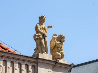 Mavi gökyüzüne karşı dış yapı üzerine yapılmış altın barok heykeller dekoratif mimari süslemeler sergiliyor