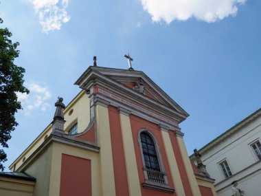 Parlak mavi gökyüzüne karşı klasik pedikürlü kırmızı ve sarı barok kilise kulesi