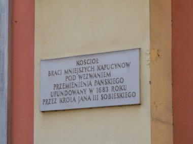 Kültürel mirası ve hafızasını gösteren renkli bina cephesine asılmış Lehçe yazılı tarihi bir plaket.