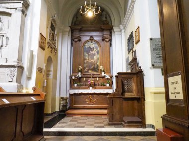 Barok kilisesinin, detaylı ahşap koro tezgahlarını ve dini sanat eserlerini gösteren yan görüntüsü.