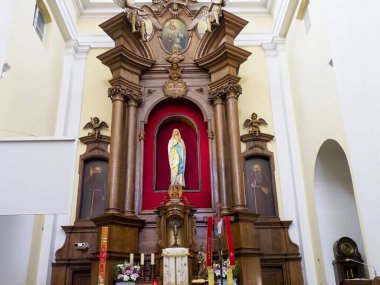 Barok kilisesinin sunağına yakından bakın. Karmaşık altın dini ikonografi ve kırmızı aksanlar içeriyor.