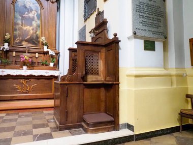 Tarihi kilise ortamında barok ahşap minber, karmaşık oymalar ve dini sanat eserleri.