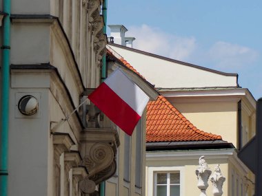 Geleneksel kırmızı kiremit çatı mimarisi ile Avrupa binasının ön cephesinden sallanan Polonya bayrağı