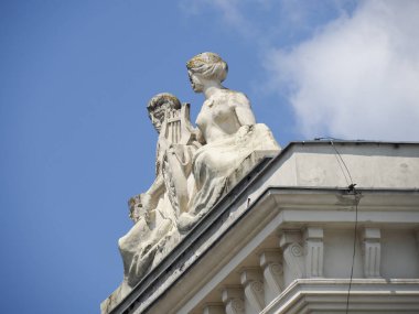 Klasik barok heykeller dramatik mavi gökyüzüne karşı tarihi bina çatılarını süslüyor.
