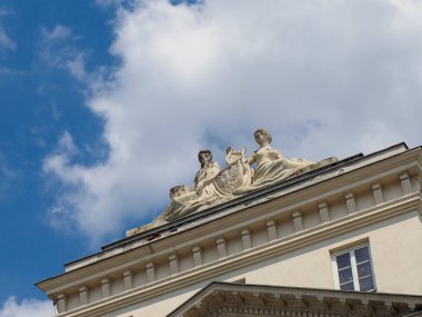 Süslü heykel süslemeleri ve bulutlu gökyüzü altında barok mimari detaylarıyla klasik Avrupa binası cephesi