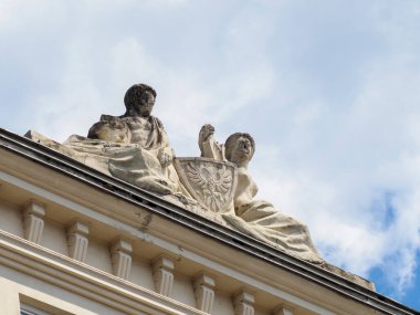 Tarihi binayı süsleyen klasik heykeltraşların detaylı görüntüsü bulutlu parlak mavi gökyüzüne karşı