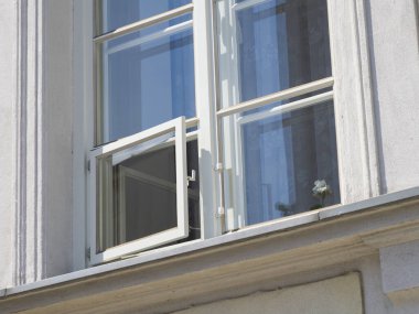 Modern cam pencere mavi gökyüzünü ve bulutları yansıtıyor.