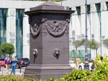 Modern şehir binaları ve kamu meydanında kentsel manzarayla çevrili yardım heykelleri olan tarihi anıt