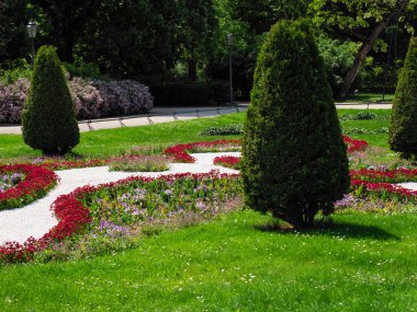 Dekoratif çiçeklerle süslü bahçeler ve mükemmel budanmış ağaç ağaçları.