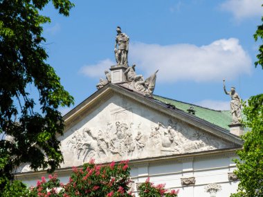 Mavi gökyüzünün altındaki yemyeşil kubbeli tarihi neoklasik bina.