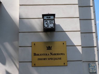 Sarı Ulusal Kütüphane Özel Koleksiyonlar tabelası beyaz bina duvarına asılmış ve ev numarası 36.