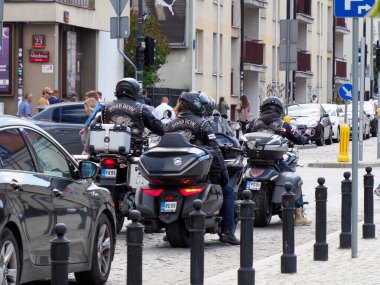 Çok sayıda siyah motosiklet ve scooterlar yerleşim yerlerinin yakınındaki park alanında düzenlenmiş.