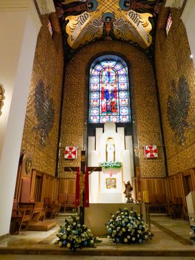 Çiçek düzenlemeleri ve sıcak ortam aydınlatmasıyla güzel vitray pencereli şık kilise sunağı.