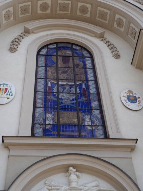 Tarihi kilise binasının süslü taş kemerinde mavi boyalı cam pencere.