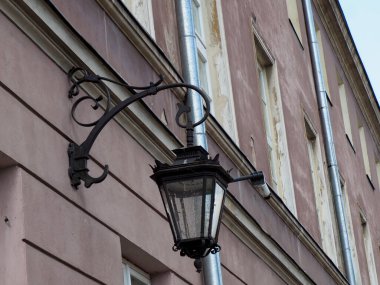 Geleneksel süslemeli sokak feneri tarihi binanın ön cephesine monte edilmiş. Eski şehirde atmosferik mimari ayrıntı yaratıyor.