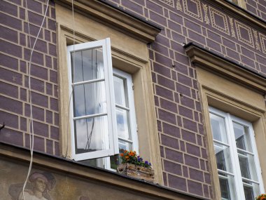 Beyaz çerçeveli pencereleri ve dekoratif çiçek kutularıyla geleneksel mimarinin yer aldığı tarihi Avrupa binası cephesi