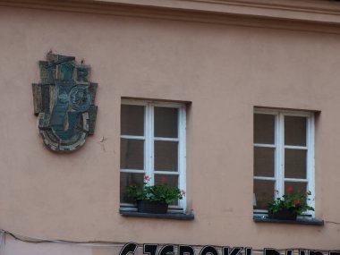 Dekoratif arma ile tarihi bina cephesi ve çiçek kutularıyla geleneksel Avrupa pencereleri