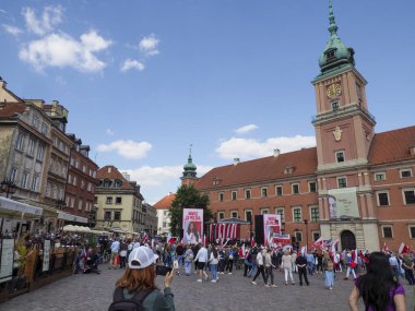 Turistlerin ve yerlilerin güneşli öğleden sonra kaynaştığı Varşova Kalesi Meydanı sahnesi