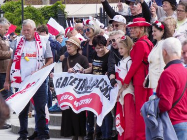 Takım eşarplı ve bayraklı bir grup Polonyalı taraftar milli takım maçında coşkuyla tezahürat yapıyor.