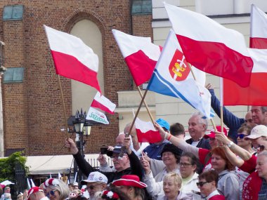 Varşova 'da tarihi tuğla binaların arka planında düzenlenen yurtsever mitinglerde büyük bir kalabalık Polonya bayraklarını sallıyor.
