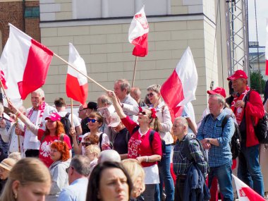 Şehir meydanında modern binalarla yapılan vatansever gösteriler sırasında elinde ulusal bayraklar tutan bir grup Polonyalı.
