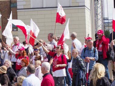 Büyük bir Polonyalı vatansever topluluğu, şehir merkezinde coşkulu bir kalabalıkla ulusal kutlama sırasında bayrak sallıyor.