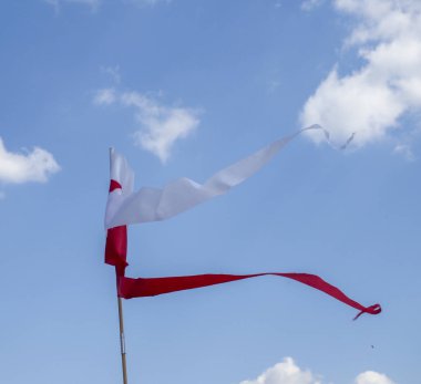 Polonya ulusal bayrağı yumuşak meltemle dalgalanır. Yumuşak mavi gökyüzüne karşı. Yumuşak beyaz bulutlarla.