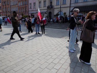 Varşova 'daki Polonya ulusal bayramı kutlamaları sırasında tarihi kaldırım taşı meydanında yürüyen bir kalabalık.
