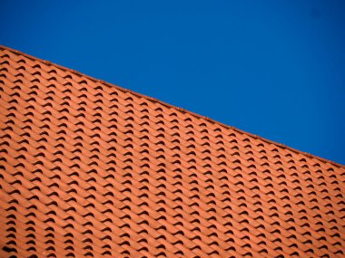 Kırmızı kil çatı kiremitlerinin tekrarlanan deseni geometrik doku ve mimari detay oluşturur