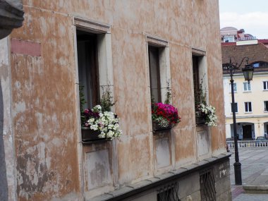 Yıpranmış duvarlarda dekoratif çiçek kutularıyla tarihi bina cephesi geleneksel Avrupa mimarisini sergiliyor