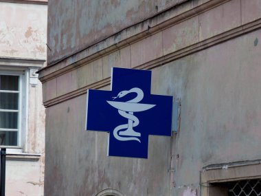 Geleneksel Avrupa eczane işareti yıpranmış bina duvarında mavi ve beyaz tıbbi sembol gösteriliyor