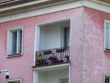 Beyaz camları ve dekoratif demir balkon korkulukları olan büyüleyici pembe konutlar.