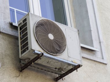 Konut pencerelerinin altındaki dış duvara monte edilmiş iki beyaz klima ünitesi.
