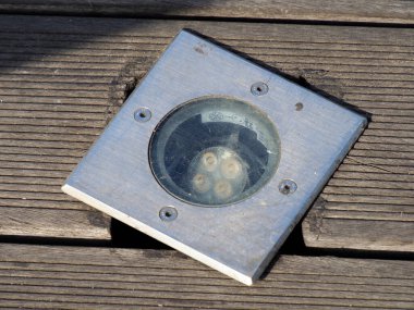 Dairesel LED zemin ışığı, ahşap güverte tahtalarını akşam saatlerinde sıcak parlaklığıyla aydınlatır.