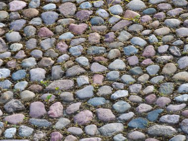 Yıpranmış doğal taş kaldırımın çeşitli renkli taşlarla yakın çekim dokusu.