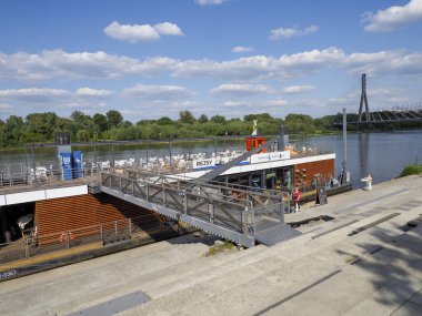 Beyaz teknesi olan yolcu feribot terminali dramatik bulutlu gökyüzünün altında beton iskeleye yanaştı.
