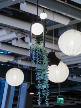 Modern ticari iç mekan askıya alınmış ekicileri yeşillik ve çağdaş ışıklandırma elementleriyle sergiliyor