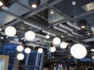 Geniş, modern restoran tavanında birden fazla beyaz dünya ışığı ve endüstriyel mimari unsurlar dramatik atmosfer yaratıyor.