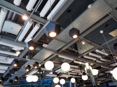 Modern endüstriyel tavan, havalandırma kanalları ve zarif kolye aydınlatma armaşıyla.