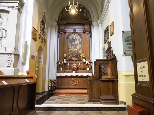 Barok kilisesinin, detaylı ahşap koro tezgahlarını ve dini sanat eserlerini gösteren yan görüntüsü.