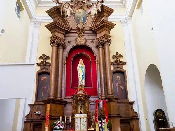 Barok kilisesinin sunağına yakından bakın. Karmaşık altın dini ikonografi ve kırmızı aksanlar içeriyor.