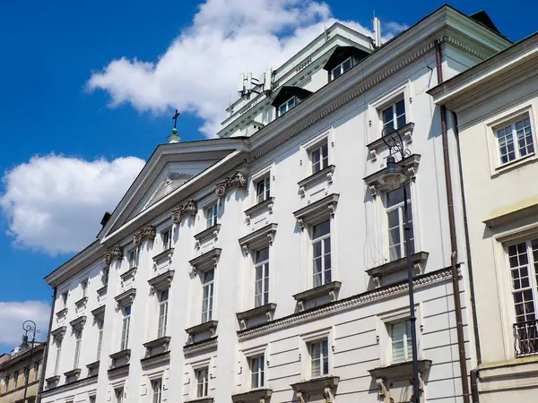 Görkemli beyaz neoklasik saray binası, bulutlu dramatik mavi gökyüzüne karşı süslü detaylar.