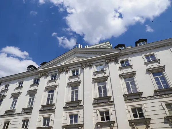 Dramatik bulutlu gökyüzü altında klasik sütunları olan beyaz neoklasik kurumsal yapı