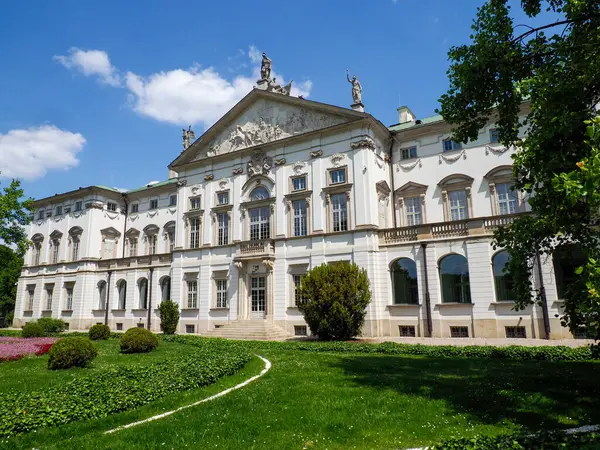 Şatafatlı bahçeleri ve güneşli bahar gününde yontulmuş çitleri olan büyük barok sarayı.