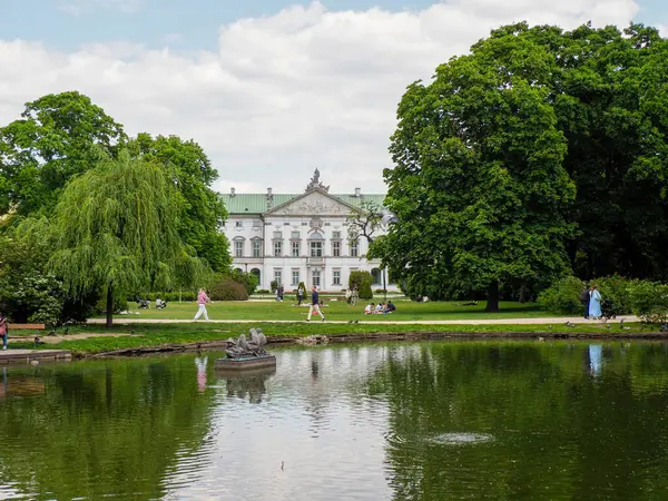 Bereketli yeşil parklarla çevrili sakin sularda yansıyan tarihi saray binası.
